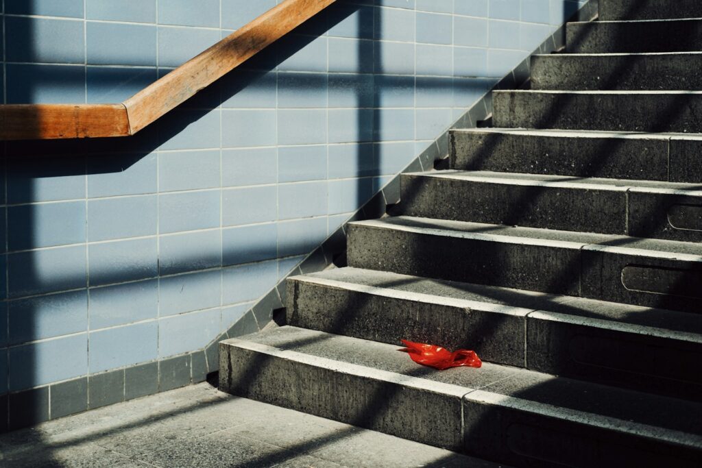 A single red object rests on a sunlit staircase.