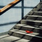 A single red object rests on a sunlit staircase.