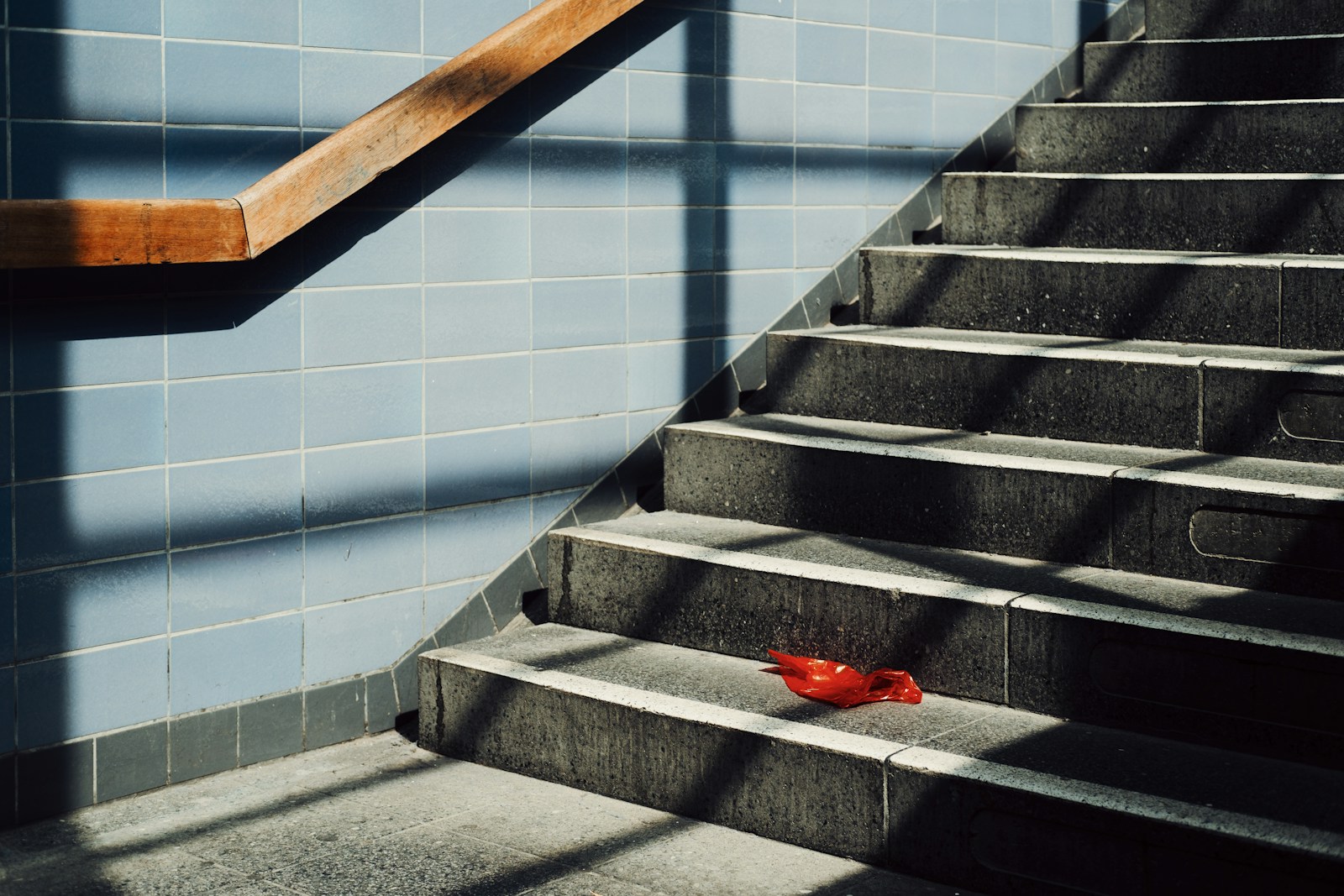 A single red object rests on a sunlit staircase.